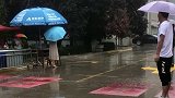 幼儿园放学遇到大雨，四个老师举伞送他们出校门，小朋友们也非常