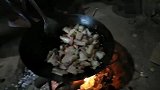 农村火坑下，炕下小锅炒着烟熏10天的腊肉，边炒边吃过瘾美味