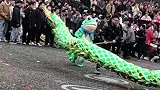 青蛙人偶跟随舞龙，围观者拍手叫好