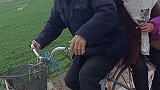 安徽阜阳：奶奶坐爷爷自行车后座，怀里捧着鲜花