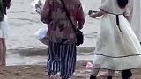 情侣在海边看海，奶奶上前送上一束花