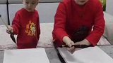 三岁小朋友跟着妈妈练习毛笔字，手随眼动一笔一划模仿母亲手法