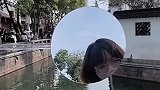 女子在镜子上作画，路人纷纷驻足观赏