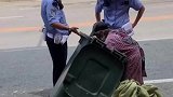 拾荒老人因手够不到垃圾桶内，一旁民警上前倾斜垃圾桶