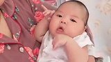 宝宝躺在奶奶的怀里抛媚眼，还不停的看着妈妈卖萌，小表情萌翻了