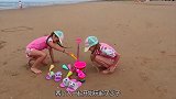 双胞胎姐妹在沙滩玩，堆沙堡打水仗，玩得很开心