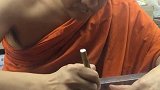 泰国僧侣在给游客签名，直接写在了钱币上