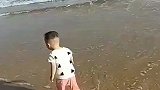 海边看到一个小宝，海浪来了麻利跑了，云南网友：我笑了！