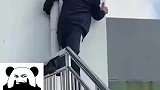 教练抱着管道踩着栏杆，趴在墙边看学员考驾照