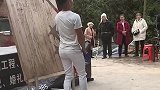 男子站在木板前，任由同伴盲扔飞镖
