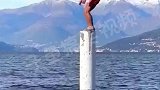 外国男子在海里的一根圆柱上起跳，龙王来了刚好吃席