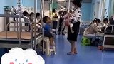 女子在医院照顾三个孩子，双手举着点滴架，怀里还背着一个孩子