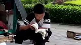 男孩早市上帮父母看摊间隙读书