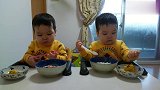 双胞胎宝宝坐在一起吃饭，一个人两个碗，看起来真好吃