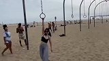 女子身穿长裙挑战海滩的吊环长桥，强大的臂力和腰腹力量