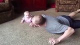 在地上，爸爸和宝宝一起做运动，真是个健康的小宝宝呀！