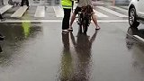 骑车人没穿雨衣，等红灯的时候，交警顺手撑起伞为他遮挡风雨