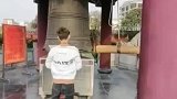 男子到寺庙跪拜求佛，兄弟在一旁敲钟祈福