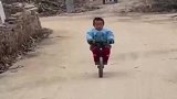 小男孩练习不用扶把骑车，跌倒不哭不闹起来继续骑