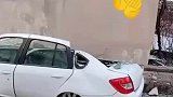 轿车卡在房子下面，路人见状疑惑不解
