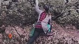 大姐迎着大潮，将身体紧贴在几乎垂直的礁石上赶海