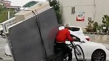 老人骑三轮车拉货被困路中，热心路人帮其脱困