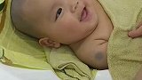 小宝宝躺在浴缸里洗澡，听到有人夸自己长得漂亮，宝宝开心的直笑