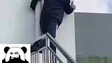 教练抱着管道踩着栏杆，趴在墙边看学员考驾照