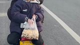 电动车上小男孩吃爆米花，等红绿灯的时候还分给后车人吃
