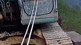 悬崖道路过于狭窄，男子用绳牵着挖掘机下山