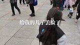 男子骑着三轮接孩子放学，还拿衣服给孩子盖着头