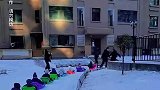 孩子们在雪地里排排坐玩雪橇长龙
