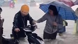 暴雨之中女子持伞，帮助外卖小哥拖拽电车，水深已经没过了膝盖！
