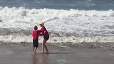 两个男孩遇到了海浪，其中一个太小瞧海浪了，被拍摔了吧！