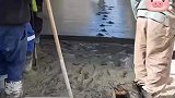 工人们刚把水泥路抹平就看见一女子脚上套着塑料袋走过去留下一串脚印