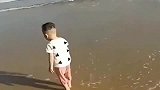 海边看到一个小宝宝，海浪来了他的反应太可爱了！