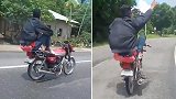 菲律宾：疯狂！男子蹲坐后座不扶方向骑摩托车
