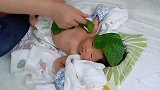妈妈往新生儿头上身上贴叶子，这宠爱方式有点特别啊！