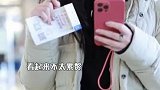 张萌举零食投喂粉丝双手比V，穿白色羽绒服，气质温柔