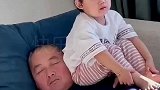 萌娃坐在外公胸前看电视，画面真是太和谐了