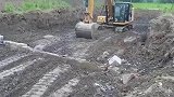 土地松软像液体，挖机师傅用挖斗回来拨弄