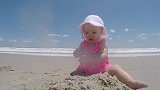 小萌娃在海滩上玩沙子正起劲，下一秒海水涨潮，小娃的表情萌翻了
