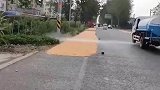 洒水车上路作业，将路边的稻谷冲毁