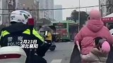 巡警在等红灯空隙帮女孩仔细戴好安全头盔，女孩回送糖果感谢