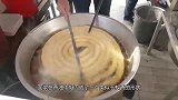大叔把油条炸成一圈“蚊香”，3块钱1份，吸引了一群观看的游客