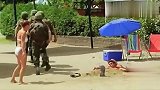 路人帮埋在沙堆的小伙拍照，士兵从他身上踏了过去