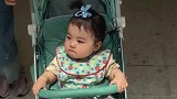 胖妹坐在婴儿车里，样子好呆萌呀