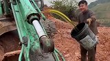 男子拿着桶接黄油，奈何黄油突然喷了出来，开挖机的都经历过吧！