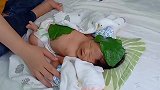 妈妈往新生儿头上身上贴叶子，这宠爱方式有点特别啊！