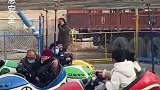 大爷单手握方向盘，护着老奶奶玩碰碰车